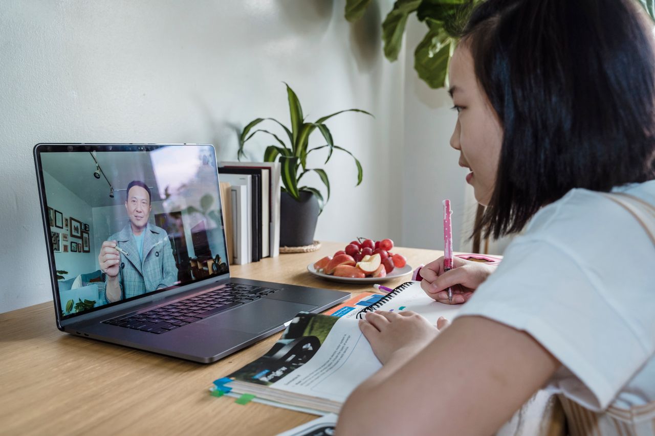 Mastering the First Impression: Your intriguing post title goes here Young girl engaged in online learning via video call, studying with laptop and notes.