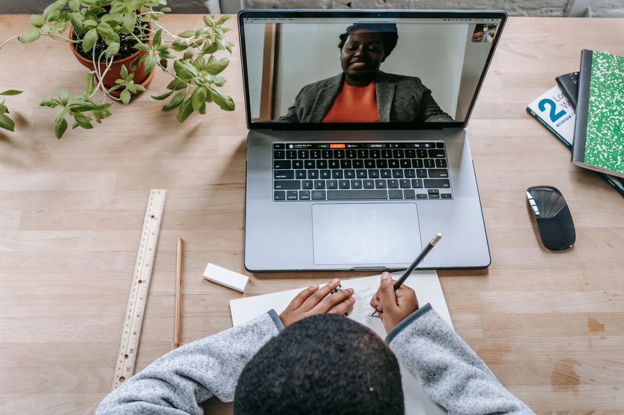The Art of Drawing Readers In: Your attractive post title goes here From above of crop anonymous black schoolchild writing in workbook against talking African American teacher on netbook screen during class